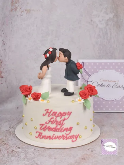 A sweet and simple cake for a first wedding anniversary. The kissing couple topper is handmade from fondant and makes for a romantic centerpiece.