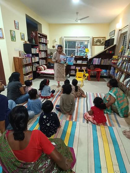 A wider view of the "magic shoes" story session, showing how parents also get drawn into the tale.