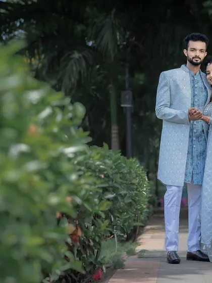 A classic couple portrait amidst lush greenery, showcasing their coordinated engagement outfits.