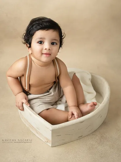 Ten-month-old twin brothers sitting in a heart-shaped basket. Their happy expressions and coordinated outfits make for an incredibly sweet portrait.