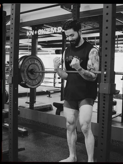 A member celebrates a good lift in the power rack. The black and white film style captures the raw, focused energy of our training floor.