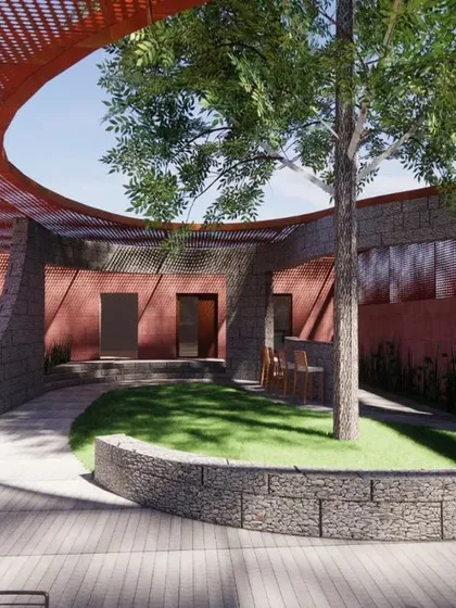 The central open-air courtyard at the Vogue Marmi experience center. This biophilic design incorporates a central tree, curved terracotta-colored walls, and natural stone, creating a tranquil space that contrasts with the polished interiors and connects the building to nature.