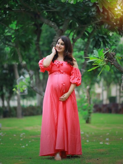 A beautiful solo outdoor portrait in a vibrant pink off-shoulder gown. The lush green background makes the color of the dress pop.