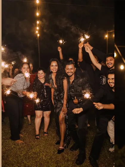A fun group photo with the couple and their friends, all celebrating with sparklers at the cocktail party.