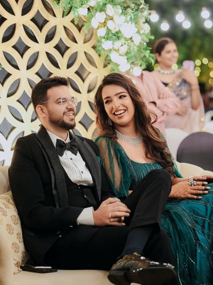 The happy couple, Pragya and Akhil, enjoying their reception. The elegant backdrop with gold geometric patterns and lush greenery was designed to create a sophisticated and warm ambiance.