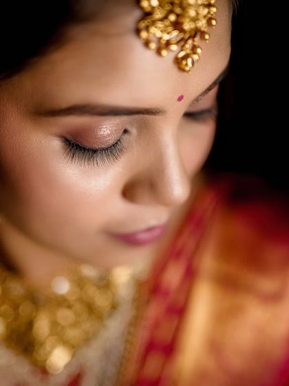Details matter in bridal photography. This intimate close-up focuses on the bride's serene expression, her flawless eye makeup, and the magnificent temple jewelry, showcasing the artistry involved in creating the complete bridal look.