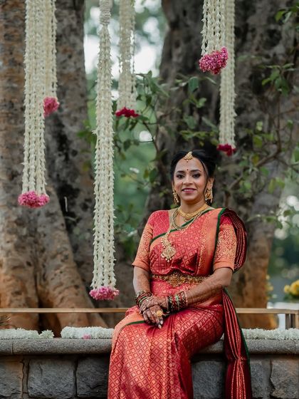 Shibani seated under a canopy of flowers for her Muhurtham. Her traditional Kanchivaram look is completed with long-lasting airbrush makeup.