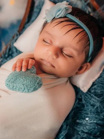 Even when they're sleeping, their little hands find the most adorable positions. This newborn girl is holding a tiny knitted heart in her dreamy, star-filled session.