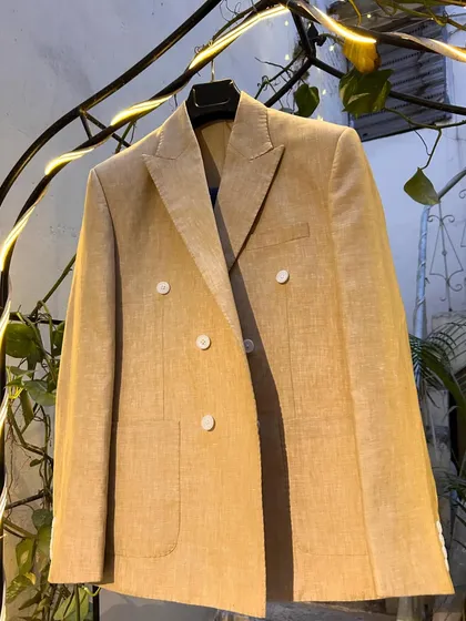 The beige double-breasted linen blazer, a timeless piece for any summer wardrobe. The peak lapels and patch pockets add a touch of classic sartorial flair.