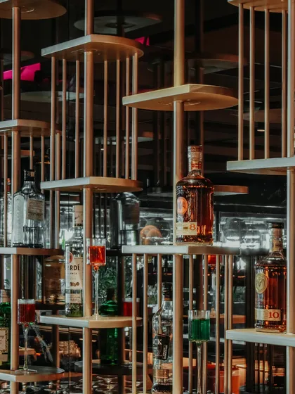 A detail of the intricate, multi-level shelving used for the bottle display. This custom-designed feature is not just for storage; it's a sculptural element that plays with light and reflection.