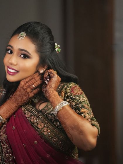A candid moment of Dr. Saruna adjusting her earring. This shot captures her elegance and the beautiful details of her reception look.