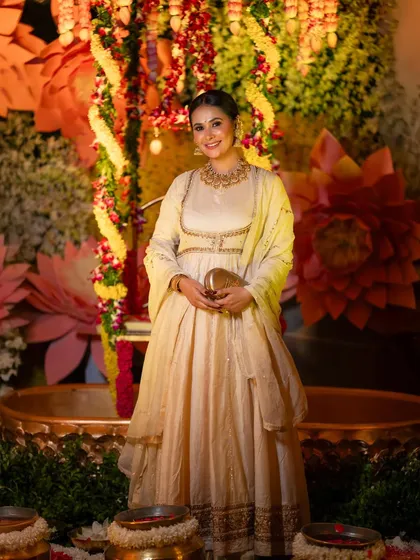 A full-length shot of Kavya Gowda, showing her entire outfit and the grand decor of the event.