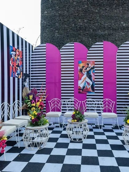 A modern, graphic photo booth area with black-and-white stripes, bold pink panels, and pop-art posters.