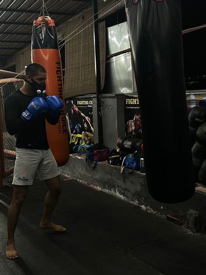 A fighter holding his guard while working the heavy bag. Proper defensive posture is drilled into every aspect of our striking training.