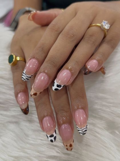 A full view of the hands with the mixed animal print nail extensions. This unique design is a testament to how creative you can get with a classic French manicure.
