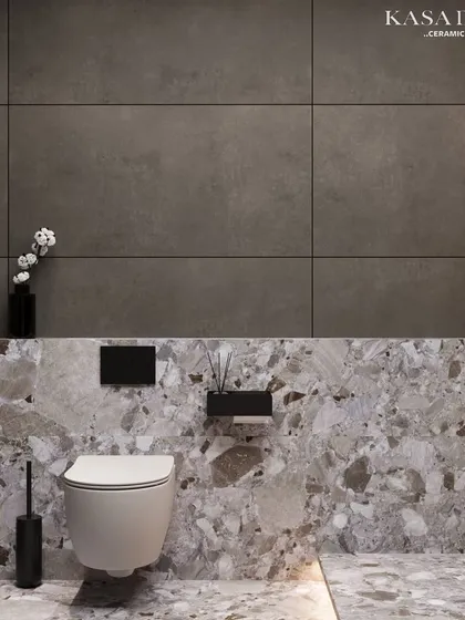 A study in texture and contrast. The lower half of this bathroom wall features a bold terrazzo-style tile, while the upper half uses large-format, concrete-effect tiles for a moody, minimalist feel.