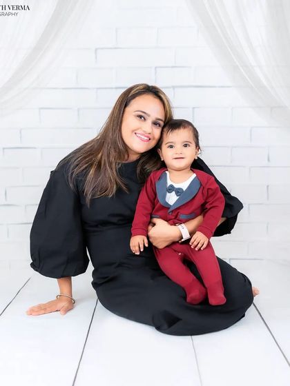 A mother and her baby boy, dressed in a cute tuxedo onesie. This is a beautiful, classic portrait capturing a mother's love.