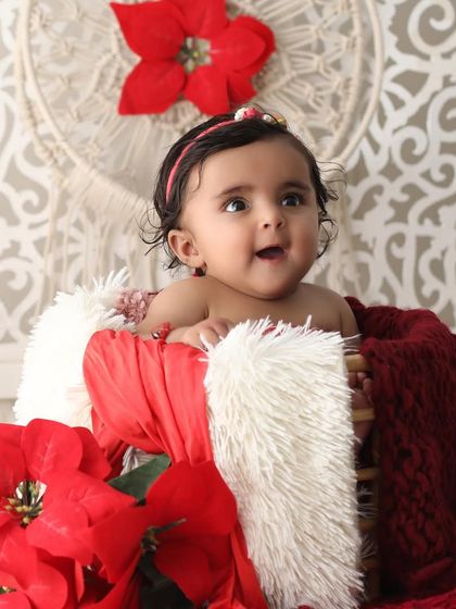 A happy and bright-eyed five-month-old baby girl. Her joyful expression is the centerpiece of this photo, taken in a festive and colorful studio setting.