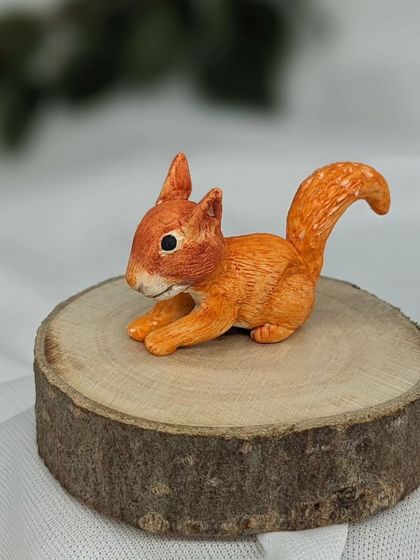 A side view of the hand-sculpted squirrel miniature, showing the texture on its bushy tail.