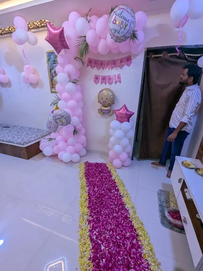 A different angle of the pink-themed welcome decor, showing how the balloon arch frames the seating area. The setup also includes a "Welcome Baby" banner and foil balloons to complete the look.