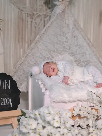 A beautiful all-white setup with a boho-chic vibe. The chalkboard with the baby's name and birthdate is a perfect way to personalize the announcement.
