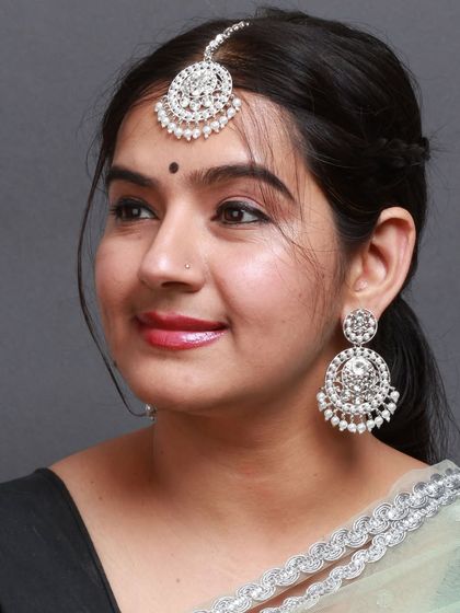 A model wearing our silver-plated stone and pearl earring and maang tika set.