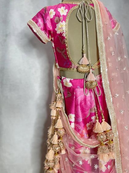 It's all in the details. This pink floral lehenga features a beautifully designed back with delicate ties and an abundance of playful latkans and tassels.