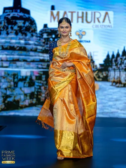 This golden-orange Kanchipuram silk saree, with its wide gold borders, is the epitome of bridal grandeur.