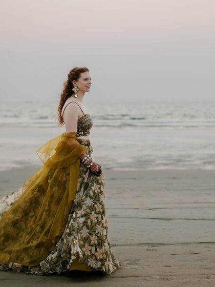 The bride's floral printed organza lehenga flows in the sea breeze. This look was all about being effortlessly elegant for their bohemian-inspired beach sundowner.