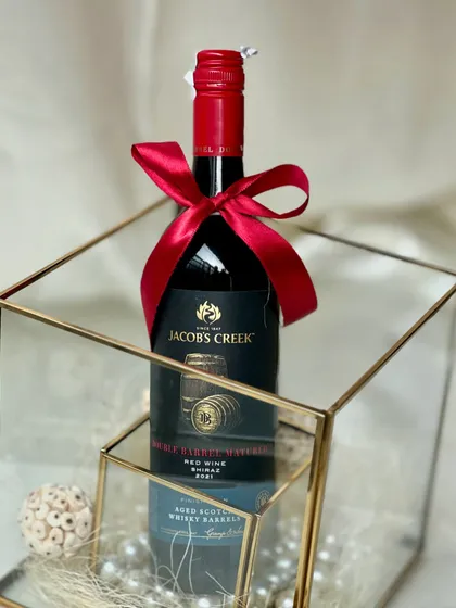 A simple yet elegant Christmas gift. This bottle of red wine, presented in a glass and gold box with pearls, is a classic choice for the holiday season.