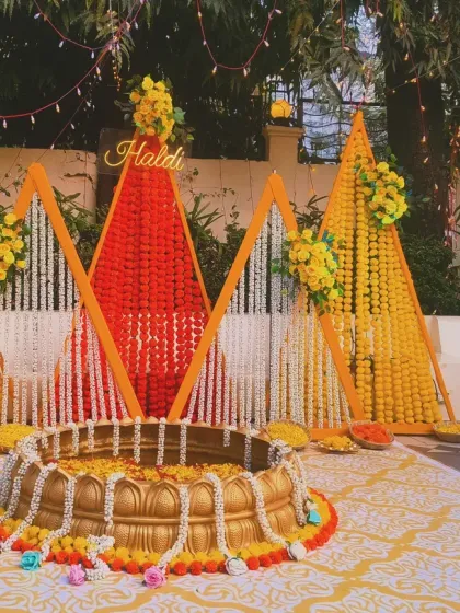 For a vibrant outdoor haldi ceremony, I designed this modern setup using geometric panels of marigold and jasmine flowers, centered around a traditional urli for the rituals.