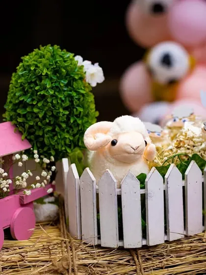 A plush sheep nestled in a tiny picket fence pen. These small, curated details are scattered throughout the party space to surprise and delight guests, adding to the immersive farm experience.