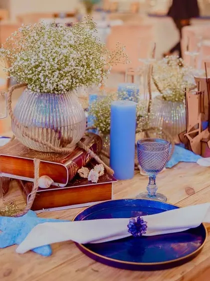 A tablescape from the nautical event, featuring blue candles, starfish, and baby's breath in a vase, all set on a rustic wooden table to evoke a seaside feel.