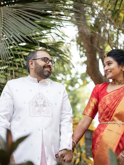 A happy couple holding hands and walking through a garden. A simple, sweet, and natural portrait.