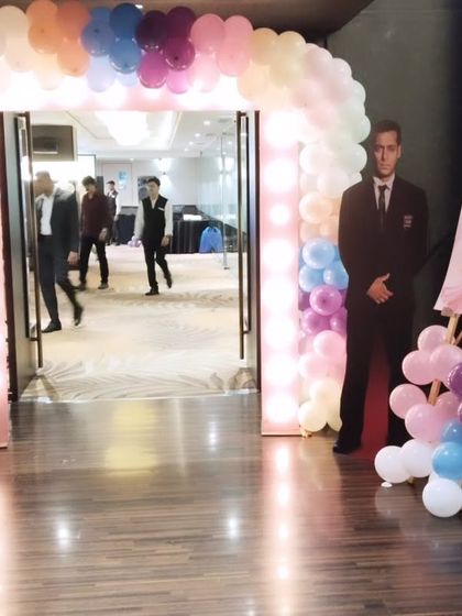Another view of the lit entrance arch, showing guests arriving at the event.