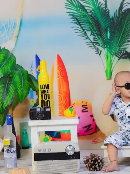 A baby boy looking very cool in sunglasses, chilling on a miniature beach chair in our vibrant and fun beach setup.