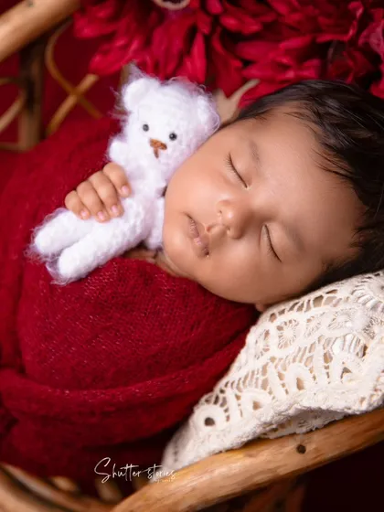 A sweet close-up of the newborn's face, nestled against a lace pillow in the maroon setup.