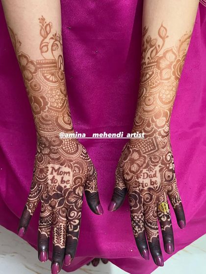 A full view of the "Mom to be" and "Dad to be" mehendi design, showing how the patterns extend elegantly up the forearms.