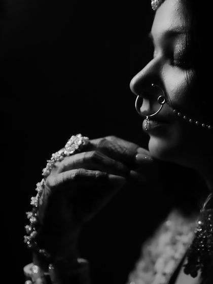 A dramatic black and white close-up of a bride's profile and her hands.