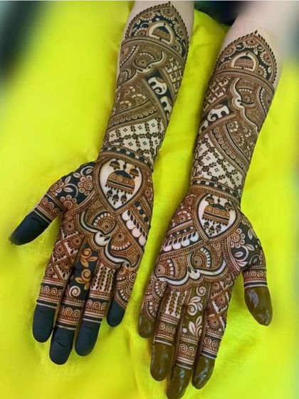 A lovely design with heart-shaped frames on the palms, each containing a doli. The arms are filled with traditional check and elephant patterns.