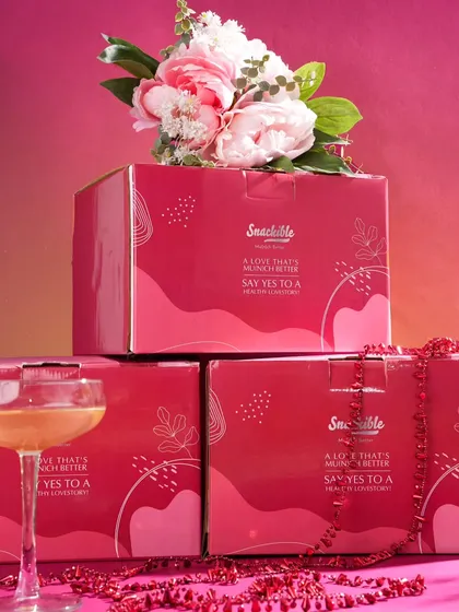 This shot focuses on the special edition Valentine's packaging. Stacking the boxes and styling them with flowers and a cocktail glass creates an elegant and celebratory image, perfect for promoting a limited-time offer.