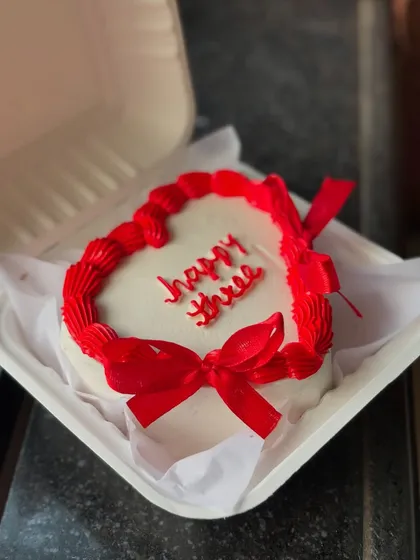 A heart-shaped bento cake for a third anniversary. The vibrant red piping and delicate ribbon bows make it a simple yet beautiful statement.