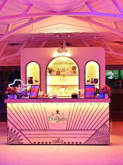 The Don Julio bar under dramatic pink lighting, showcasing its striking design and how it transforms into a vibrant centerpiece for an evening party.
