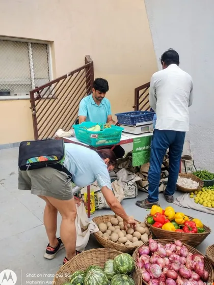 A customer in shorts and a t-shirt selecting potatoes, embodying the "pajama-chappal" market vibe.