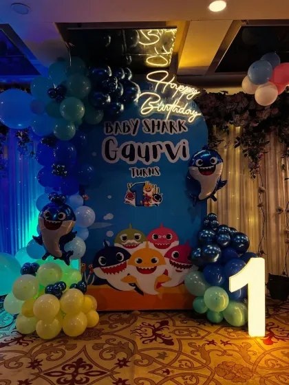 I bring popular kids' themes to life, like this fun Baby Shark party for Gaurvi's first birthday. The setup includes a custom character backdrop, a blue balloon arch to create an underwater feel, and a light-up number '1' for that perfect first birthday photo.