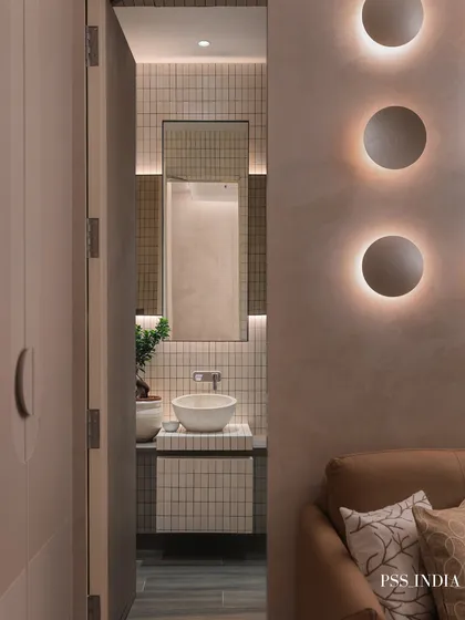 A peek into the ensuite bathroom from the guest room reveals a cohesive design story. The minimalist tiles and sculptural basin echo the modern, serene aesthetic of the bedroom.