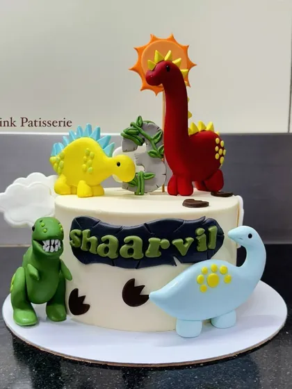 A fun dinosaur-themed cake featuring four different types of colorful, handcrafted fondant dinosaurs. The design includes dino footprints for an extra touch.
