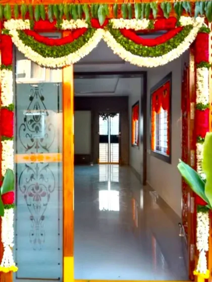 A traditional South Indian style entrance decoration for a housewarming ceremony. This welcoming arch is crafted with fresh flowers, mango leaves, and banana stems, signifying prosperity and a warm welcome.