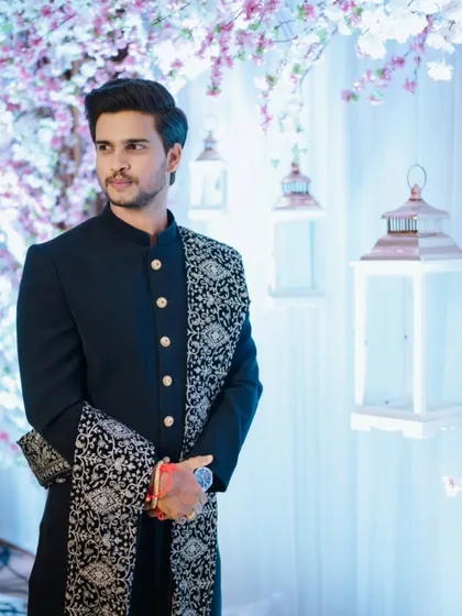A sharp portrait of the groom, Siddhesh, looking dapper in his black bandhgala against a beautifully lit backdrop at his engagement in Khar, Mumbai.