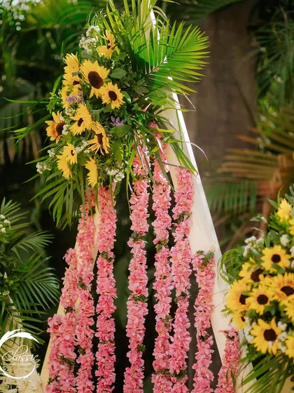 A close-up of the floral backdrop, where I combined strings of pink flowers with bunches of sunflowers and palm leaves to add a pop of contrasting color and a tropical touch.